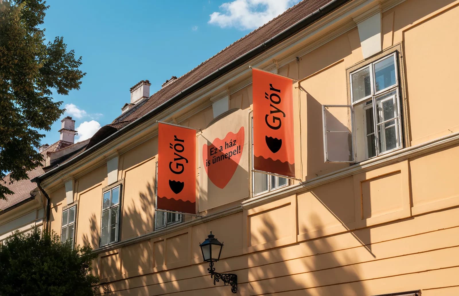 Piros Győr-zászlók egy sárga homlokzaton